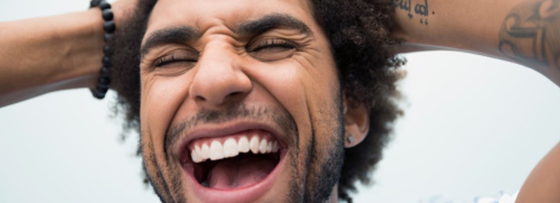 Homem feliz porque garantiu um sorriso branco e saudável usando o creme dental Sorriso Carvão Ativado
