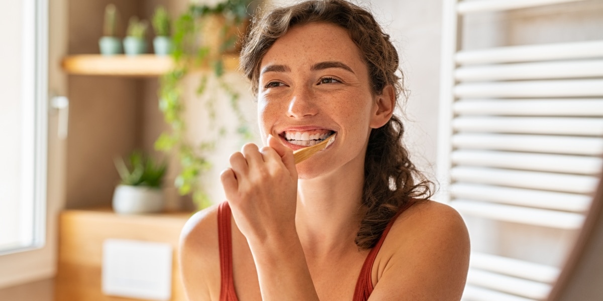 Mulher jovem escovando os dentes com Sorriso